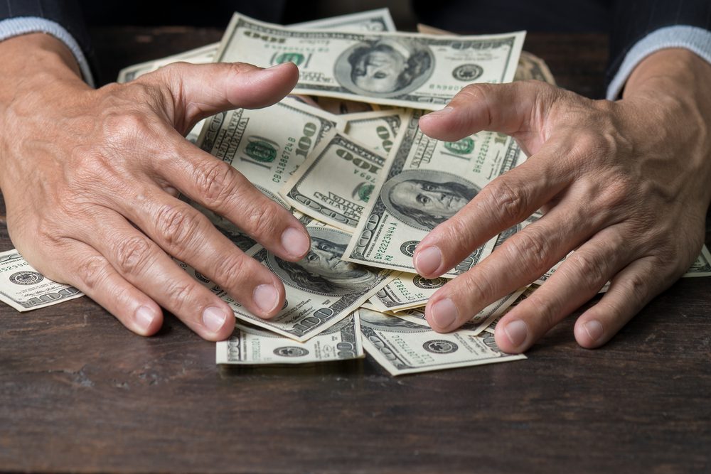 ManHandsInPinstripeSuitSweepingPileOfUsBanknotes | ForexMag Top 10 Finance Shows, Personal Finance Education, Investment TV Programs, Finance TV Shows