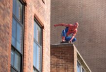 El nuevo Spider-Man rompe el récord de taquilla de fin de semana de estreno en Norteamérica Spider-Man action figure crouching on a brick ledge of a building behind tall windows.